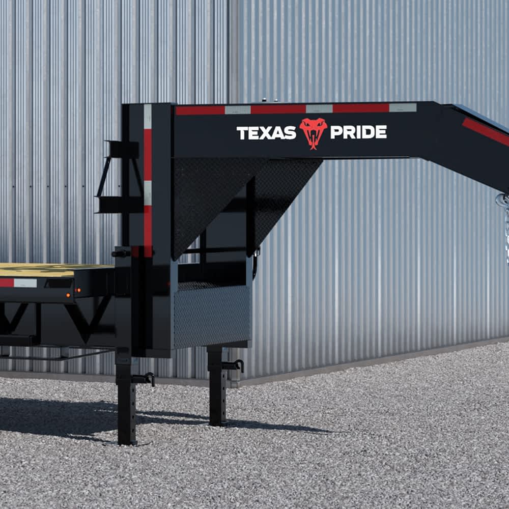 A section of a black Texas Pride flatbed trailer is shown against a backdrop of a light gray metal wall. The trailer features the white "TEXAS" and "PRIDE" lettering flanking a red longhorn skull logo, along with red and white reflective safety markings.