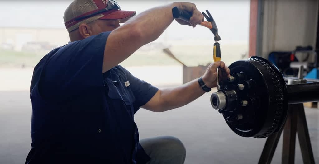 Man shows how to remove the cap from a trailer axle.