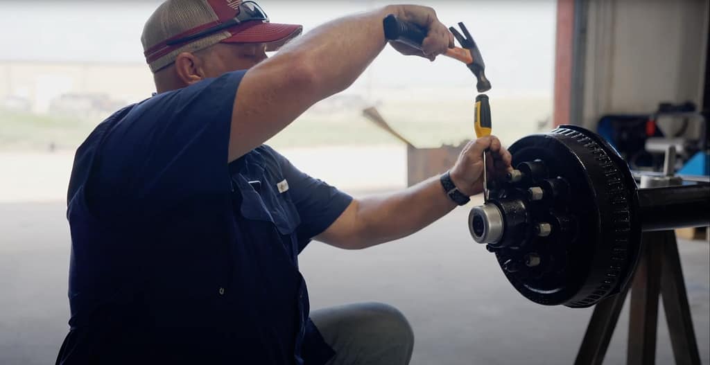 Man shows how to remove the cap from a trailer axle.