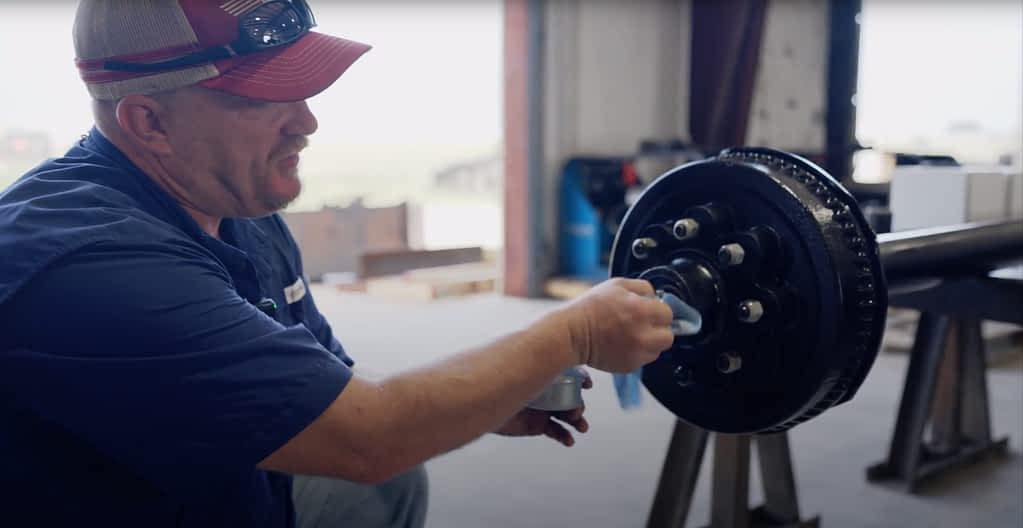 Man shows how to clean grease on a trailer axle.
