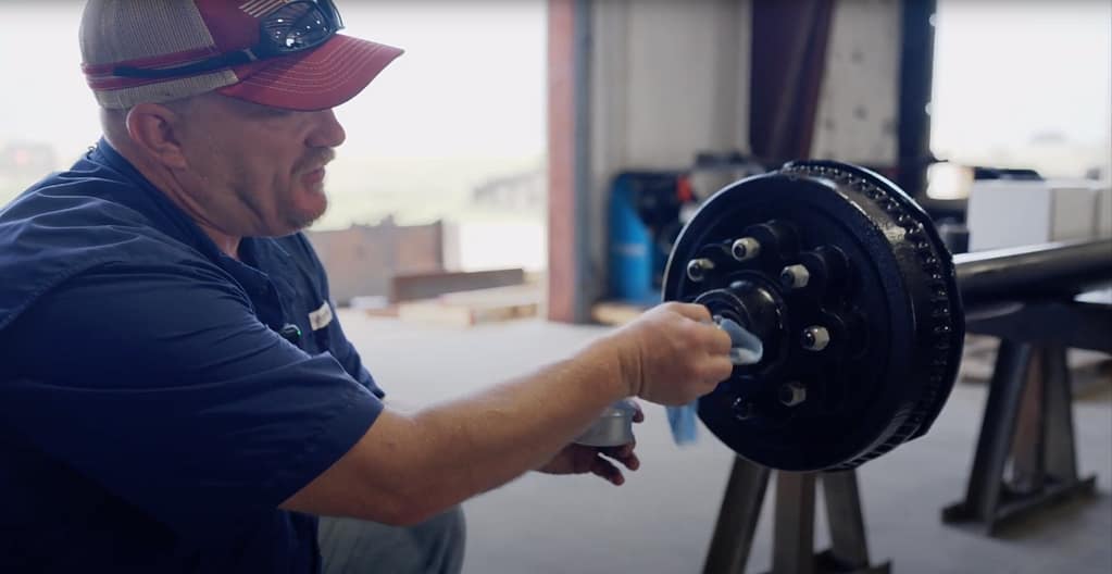 Man shows how to clean grease on a trailer axle.