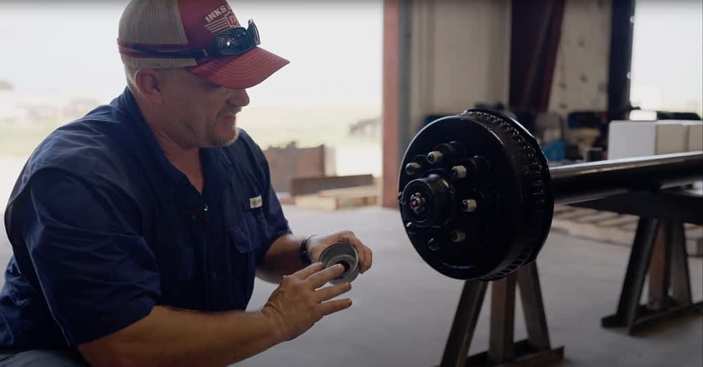 Man shows how to add the cap back on after greasing a trailer axle.