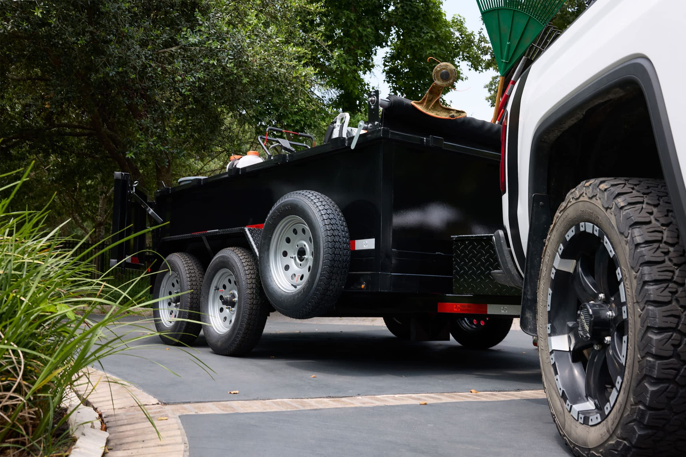 A truck towing a dump trailer for landscaping work.