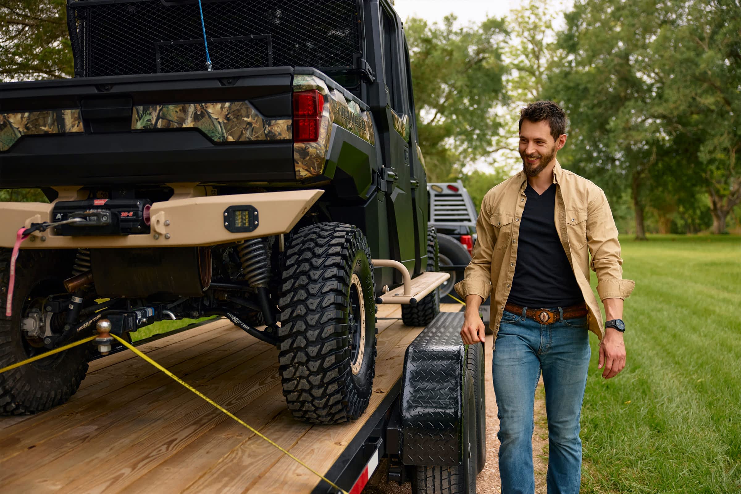A man walks alongside a trailer loaded with an OHV.