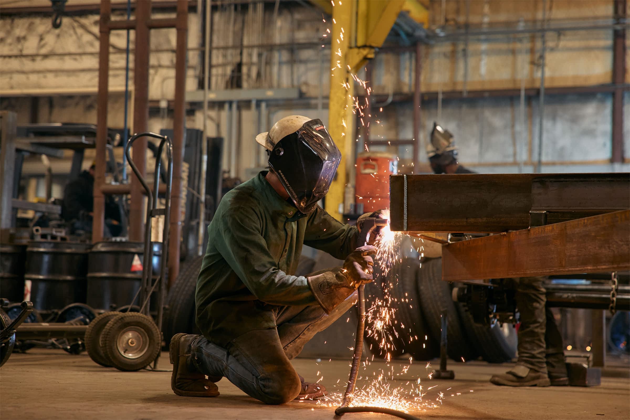 A welder working on a trailer while sparks fly.