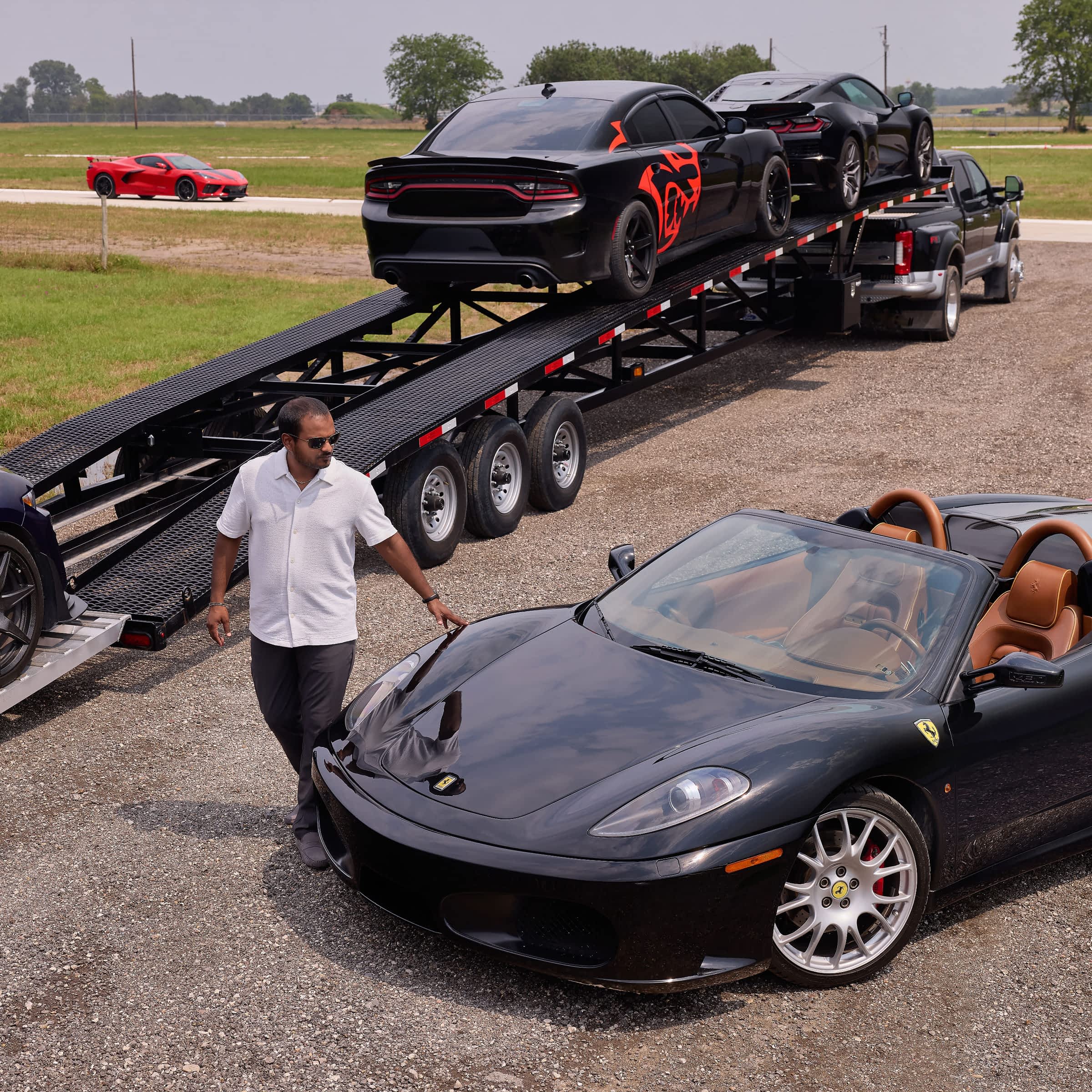 A truck with a vehicle transport trailer and sporty cars