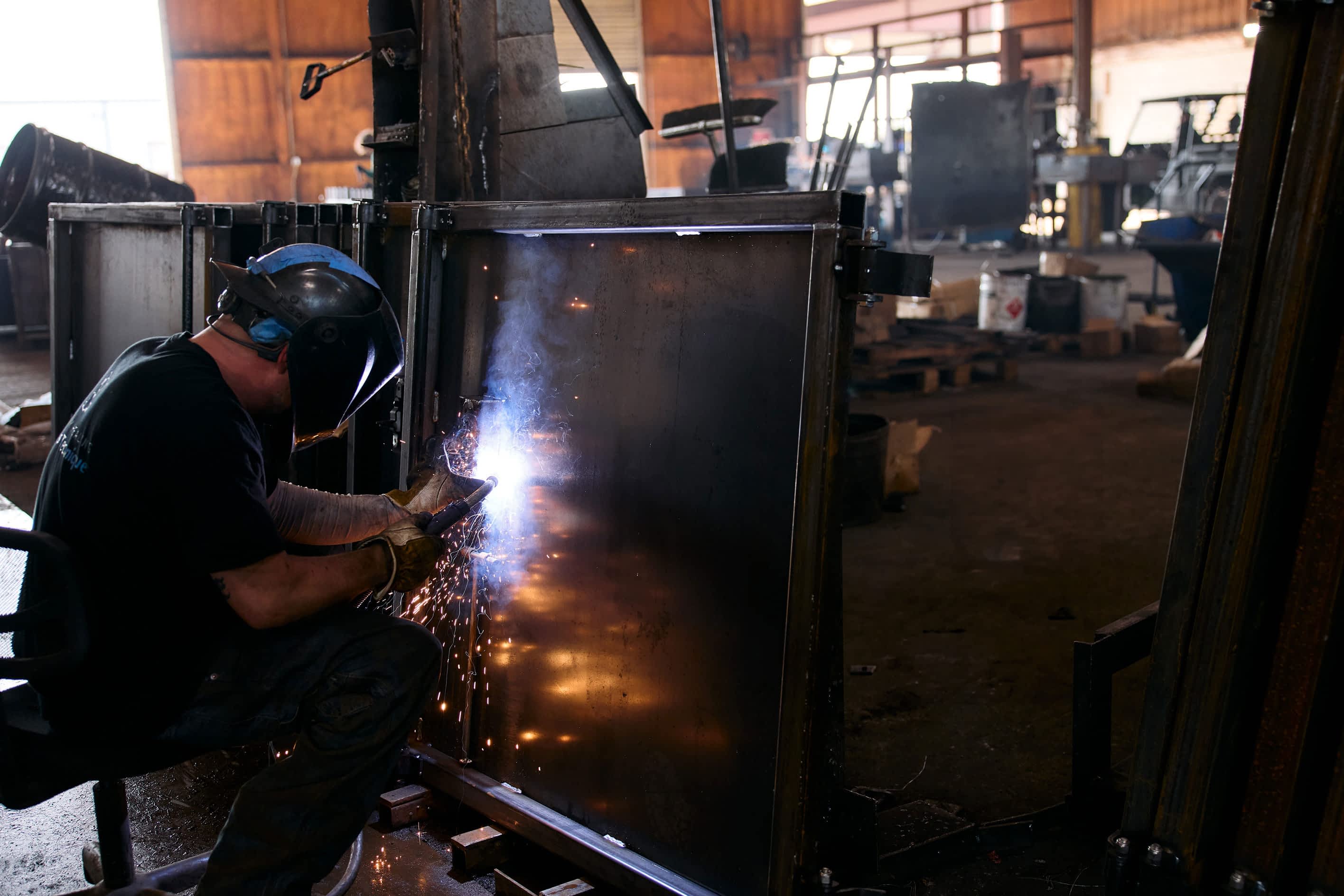 Texas Pride Trailers welder fabricating heavy-duty steel components inside the Madisonville, Texas manufacturing facility, with sparks flying during precision welding work.