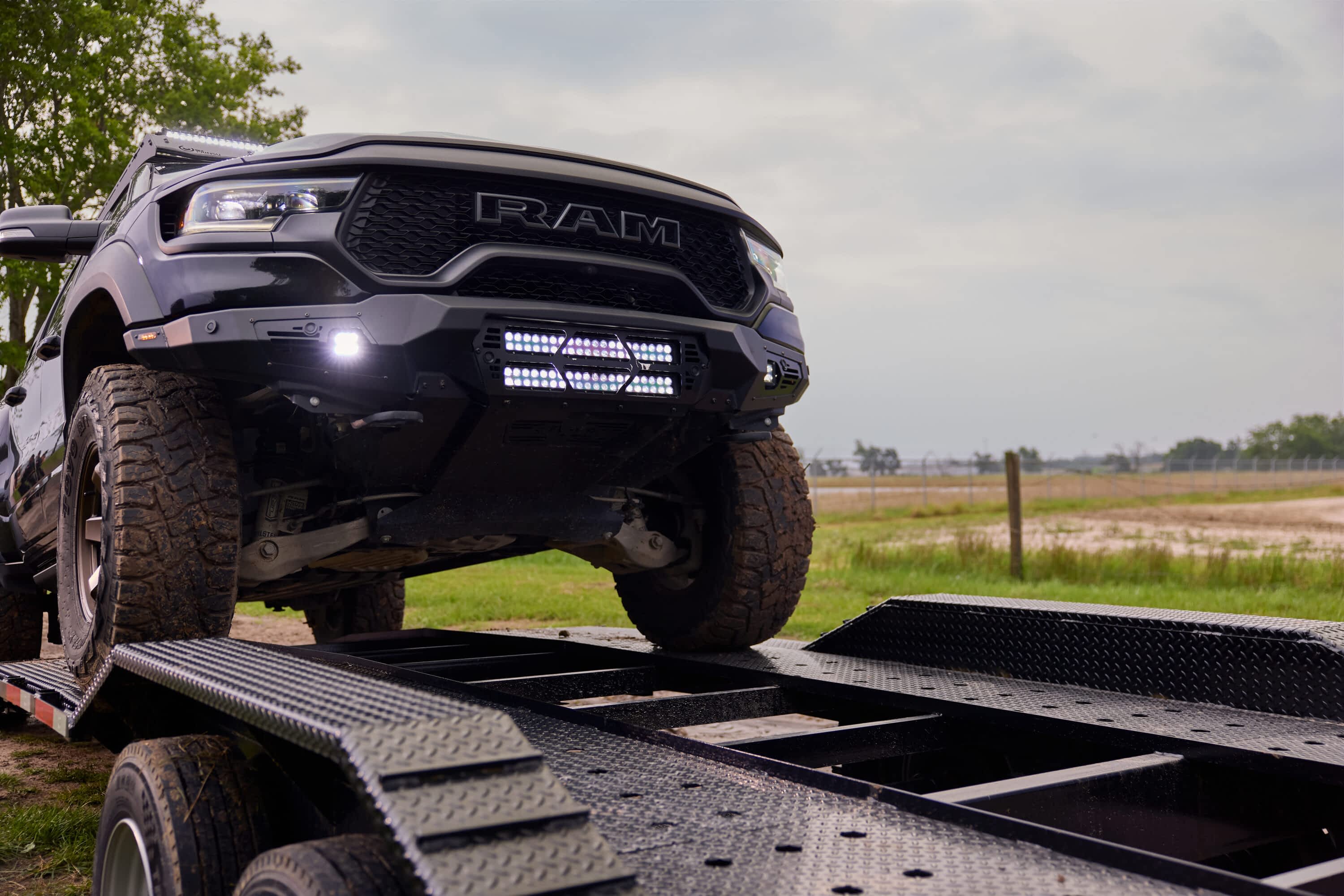 The front of a black Ram truck is loaded onto a Texas Pride Trailers car hauler trailer.