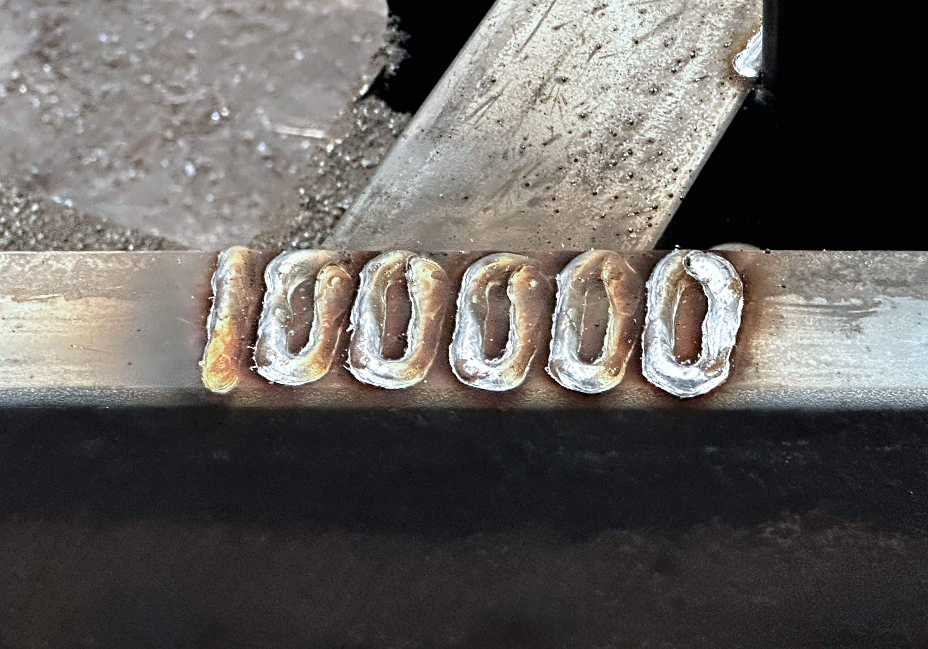 Close-up of “100000” hand-welded into the steel frame of Texas Pride’s milestone trailer—marking the 100,000th trailer built at the factory.